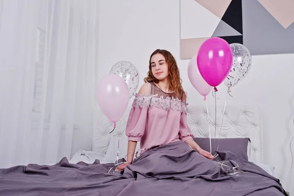 Νεαρό κορίτσι με μπαλόνια σε κρεβάτι που θέτεται στο δωμάτιο στούντιο. — Φωτογραφία Αρχείου