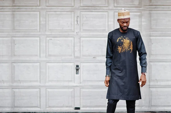 Rico homem africano em roupas tradicionais elegantes e chapéu posou ag — Fotografia de Stock