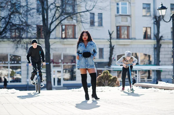 African american girl in jeans dress and two street boys jump on