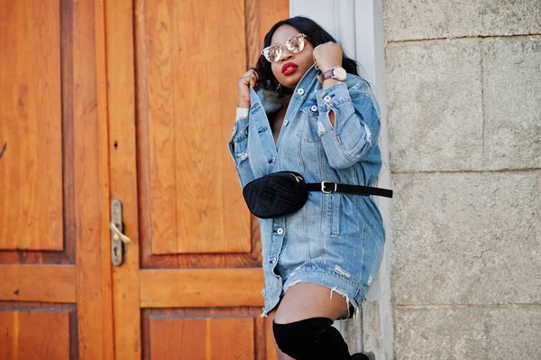 African american girl in jeans dress and sunglasses posed on str — Stock Photo, Image