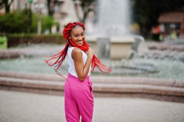 Pembe pantolon ve kırmızı moda Afro-Amerikan kız p ödü kopar.