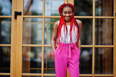 Pembe pantolon ve kırmızı moda Afro-Amerikan kız p ödü kopar.