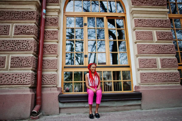 Modische afrikanisch-amerikanische Mädchen in rosa Hosen und roten Dreadlocks p — Stockfoto