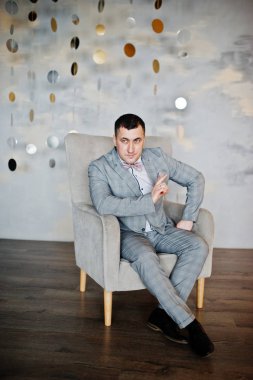 Stüdyo portre sandalye yakınındaki takım elbiseli adam.