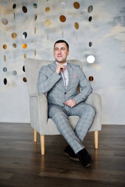 Stüdyo portre sandalye yakınındaki takım elbiseli adam.