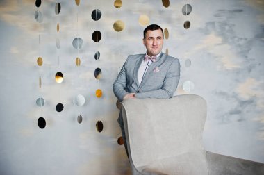 Stüdyo portre sandalye yakınındaki takım elbiseli adam.