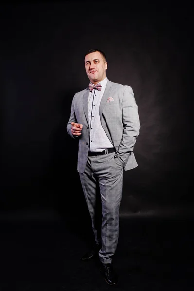 Studio portrait of man in gray suit and bow tie showing firnger — Stock Photo, Image
