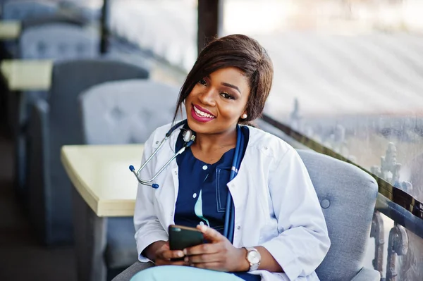 African american läkare kvinna med stetoskop tittade på telefon — Stockfoto