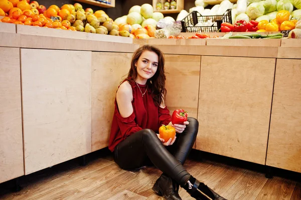 Girl in red holding two peppers on fruits store. — Stock Photo, Image