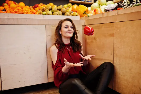 Girl in red throw peppers on fruits store. — Stock Photo, Image