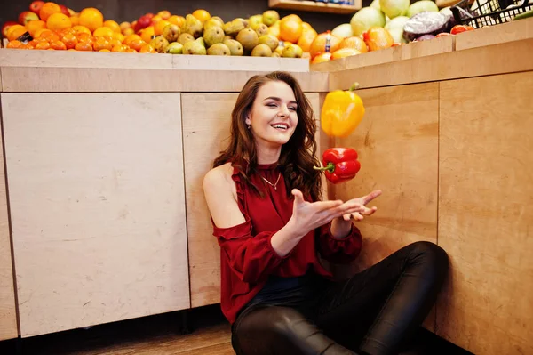 Girl in red throw peppers on fruits store. — Stock Photo, Image