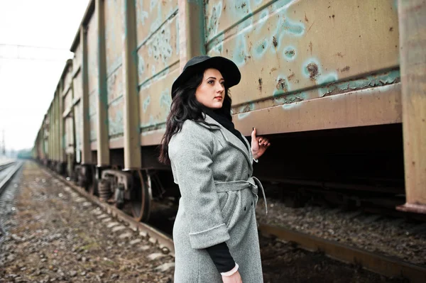 Brunett tjej i grå päls med mössa i järnvägsstation. — Stockfoto