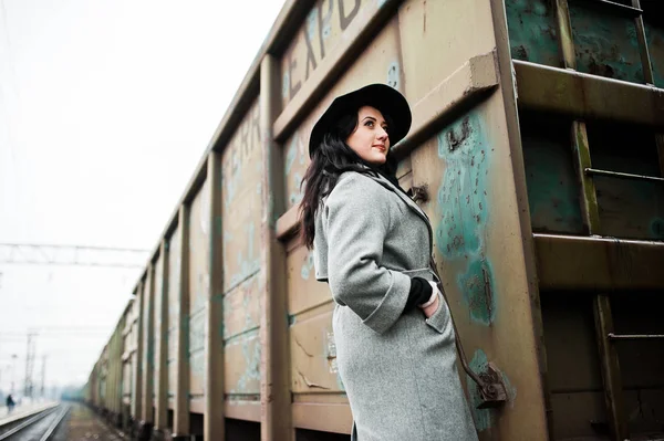 Brunette fille en manteau gris avec chapeau dans la gare . — Photo