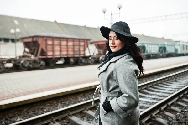 Brünettes Mädchen im grauen Mantel mit Hut im Bahnhof. — Stockfoto