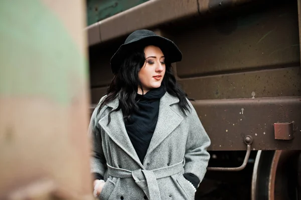 Chica morena en abrigo gris con sombrero en la estación de tren . — Foto de Stock