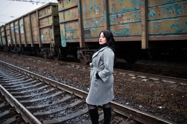 Brunette girl in gray coat posed in railway station. — Stock Photo, Image