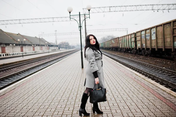 Menina morena em casaco cinza posado na estação ferroviária . — Fotografia de Stock