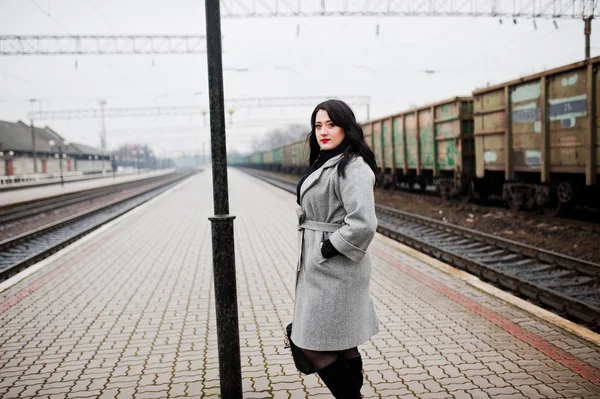Brunette girl in gray coat posed in railway station. — Stock Photo, Image