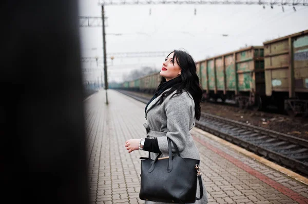 Brunette fille en manteau gris posé dans la gare . — Photo
