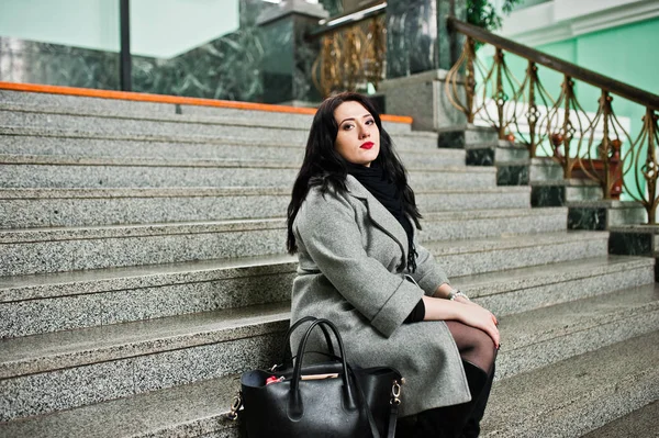 穿灰色大衣的黑发女孩在火车站的楼梯摆在 — 图库照片