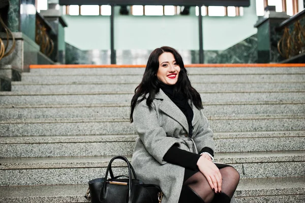 Brunette fille en manteau gris posé dans les escaliers de la gare en — Photo