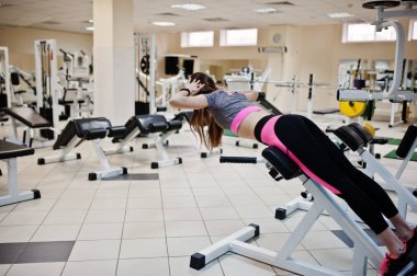 Spor salonunda egzersiz yaparken genç esmer seksi ince kız. Sportif güzel model egzersizleri yapıyor
