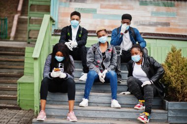 Parktaki bir grup Afrikalı genç, tıbbi maske takarak Coronavirus virüsü virüsünü karantinaya almaktan korunuyor..