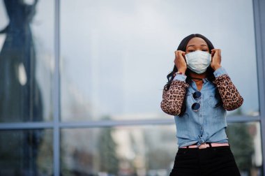 Açık havada yüz maskesi takan Afro-Amerikalı genç gönüllü kadın. Coronavirus karantinası ve küresel salgın.