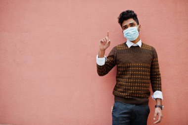 Coronavirus covid-19 konsepti. Pembe arka planda izole edilmiş Corona virüsünden korumak için maske takan Güney Asyalı bir adam..