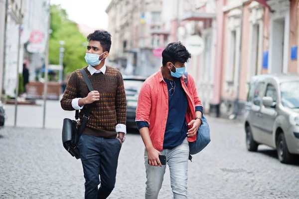 Coronavirus covid-19 concept. Two south asian indian man wearing mask for protect from corona virus walking at city. New normal lifestyle post pandemic in India.