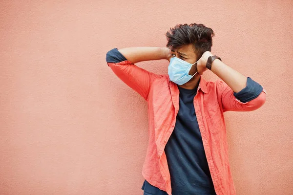 Coronavirus covid-19 concept. South asian indian man wearing mask for protect from corona virus isolated on pink background.