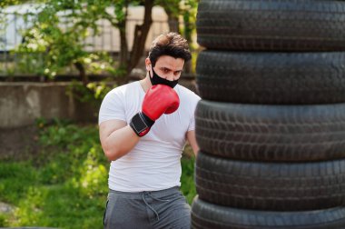 Siyah tıbbi maskeli boksör, Coronavirus karantinası sırasında dışarıda boks yapıyor..