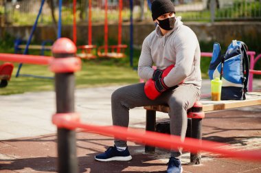 Siyah tıbbi maskeli boksör, Coronavirus karantinası sırasında dışarıda boks yapıyor..
