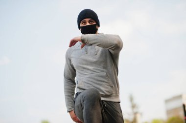 Siyah tıbbi maskeli Arap portresi Coronavirus karantinası sırasında açık havada koşar..