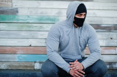 Coronavirus karantinası sırasında siyah tıbbi yüz maskesi ve kapüşonlu Arap portresi.