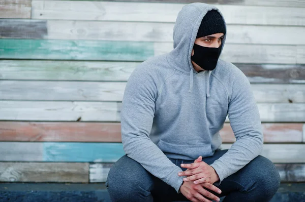 Coronavirus karantinası sırasında siyah tıbbi yüz maskesi ve kapüşonlu Arap portresi.