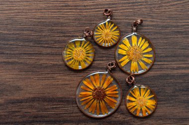 handmade epoxy resin jewelry. pendant. calendula officinalis flower in copper frame. dried flowers. herbarium, oshibana, phytotherapy. clipart