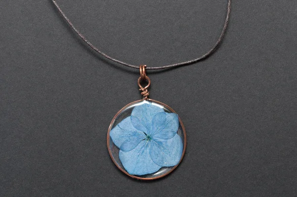 handmade epoxy resin jewelry. pendant, hydrangea in copper frame. dried flowers. herbarium, oshibana, phytotherapy. isolated on black background