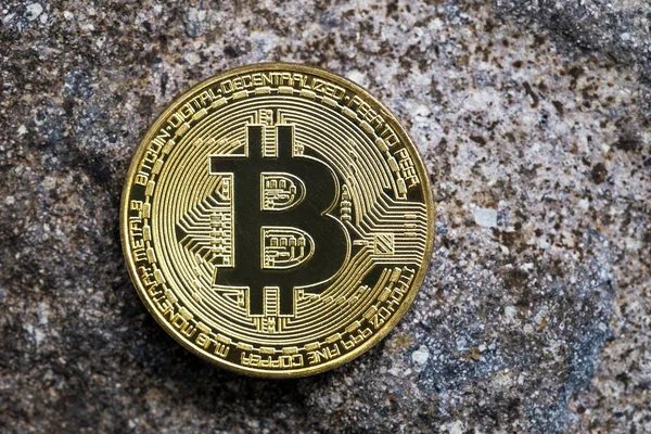 Golden bitcoin on stone surface. Stock Picture