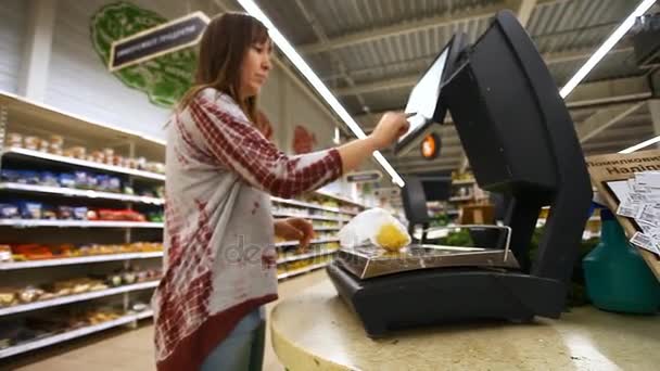女の子がスーパー マーケットで電子秤の購入を重さ — ストック動画