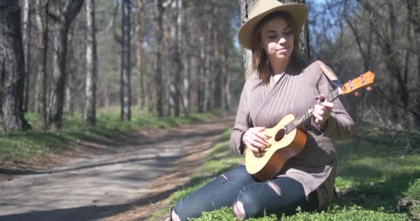 Hermosa joven con ukelele en la naturaleza — Vídeos de Stock