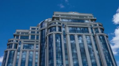 Zaman aşımına uğramış beyaz bulutlar büyük bir ofis binasının camlarına yansıyor