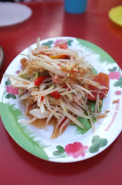 Салат папайя (сом тум тайский) на красном столе — стоковое фото