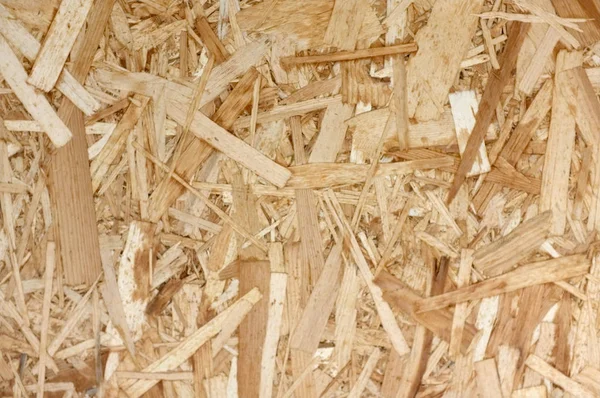 Placas OSB ou lascas de madeira marrom lixadas em um fundo de madeira . — Fotografia de Stock