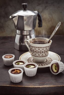 Çikolatalı tatlılar, hoş kokulu kahve ve koyu ahşap bir masa üzerinde bir kahve kabı.