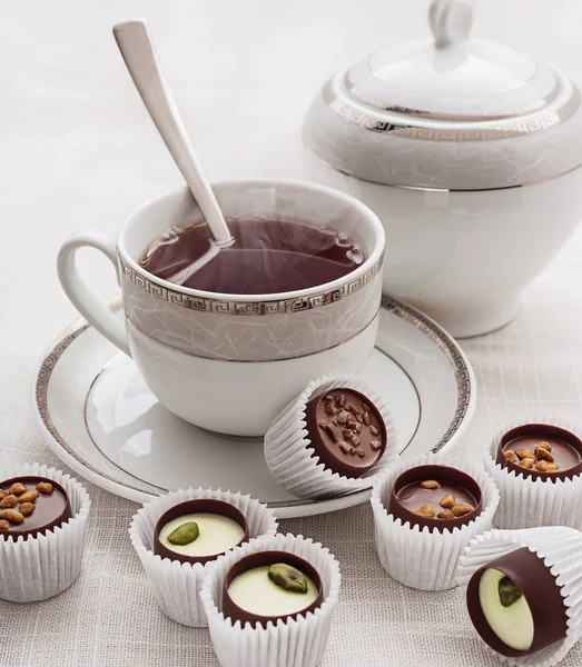 Dulces de chocolate y té caliente sobre blanco . —  Fotos de Stock