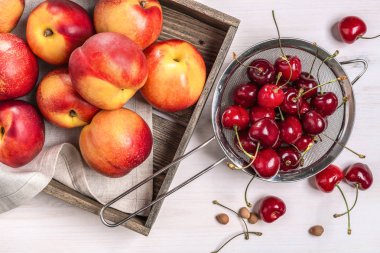 Küçük bir kevgir ve nektarin bir kutu içinde kiraz.