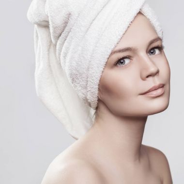 genç kadın yakın çekim portre sağlıklı deri baş üstünde yüz ve banyo havlu ile. beyaz izole