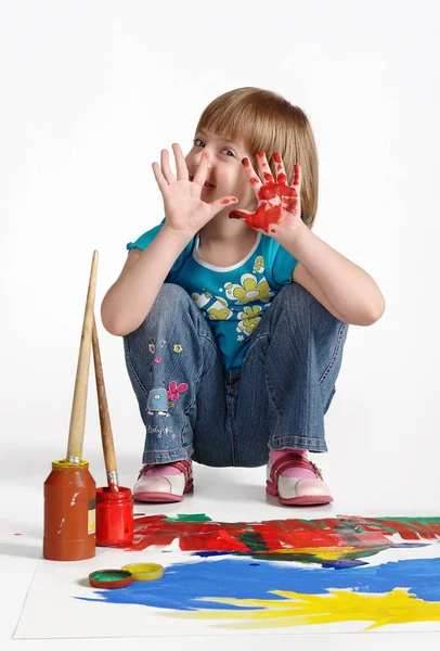 Rolig liten flicka på vitt i studio. Händer i paint. Grimas. — Stockfoto