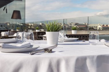  Beyaz masa örtüsü ve aletleri içeren tablo. Arka planda, sen-ebilmek görmek şehir.